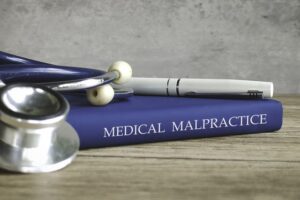 Stethoscope and a pen on a book titled MEDICAL MALPRACTICE, representing legal issues in healthcare.